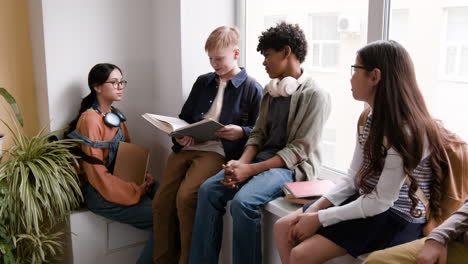diverse group of students reading and discussing by a window