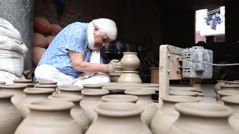 man making clay pot on spinning wheel