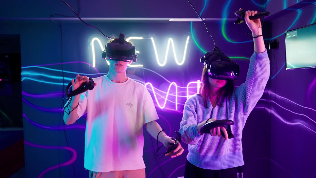 Due giovani che giocano a un gioco di realtà virtuale in una stanza illuminata al neon