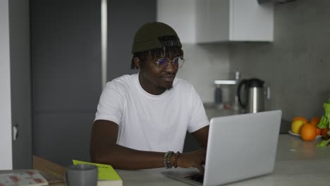Focused african black male student using laptop, typing on keyboard
