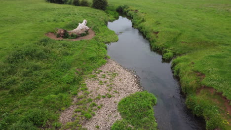 An-aerial-view-of-the-small-river-Arrow-running-through-the-green-fields-of-Warwickshire,-England