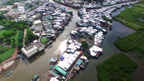 4k aerial drone view of poor dense traditional fishing village houses on stilts built on a river canal in hong kong, tai o lantau island