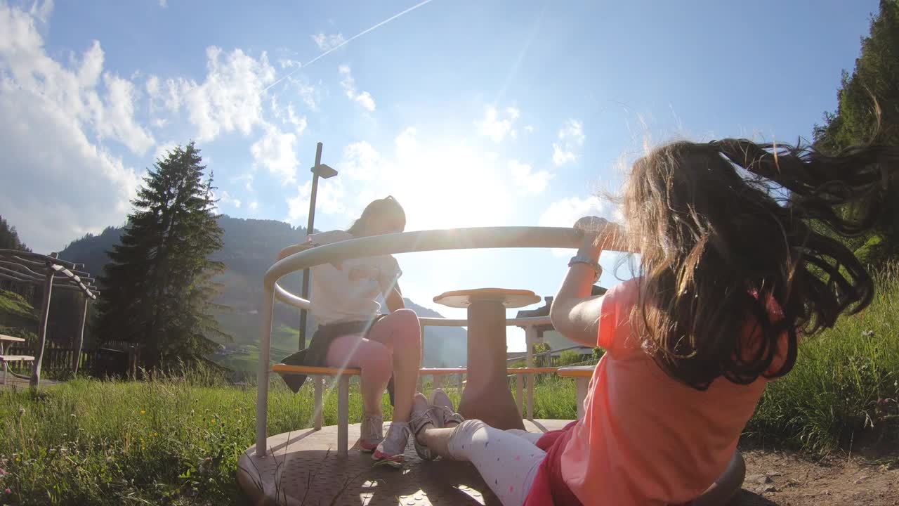 산악 공원의 회전하는 교차로에서 놀고 있는 두 명의 어린 십대 소녀. dolomites, trentino, italy.