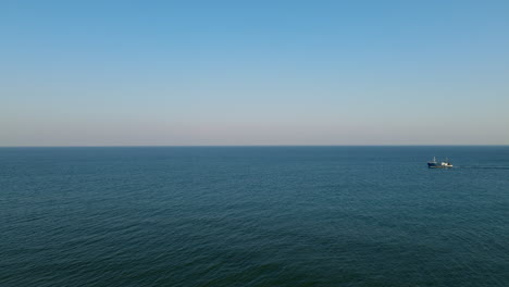 aerial wide shot of ship cruising on endless ocean during beautiful blue sky and sunlight