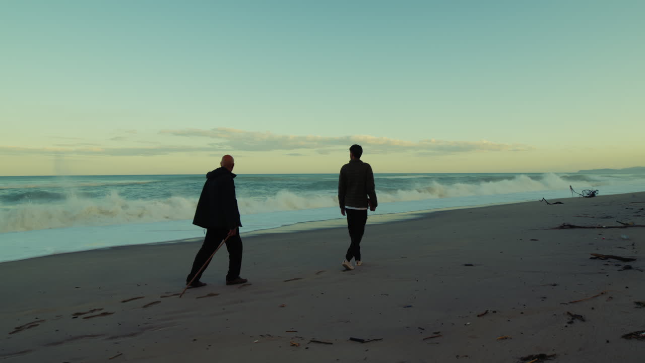Silhouette Of Two Men Walking In Nature Beach At Morning Time