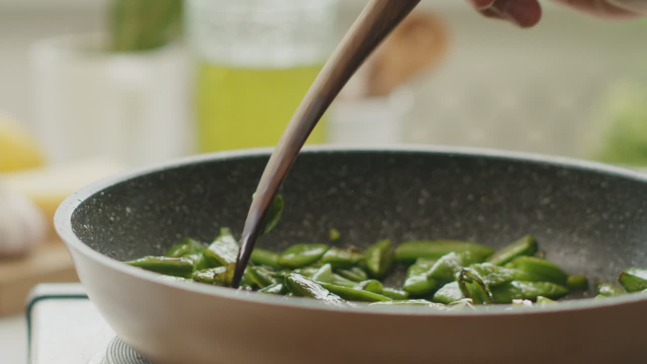 mujer de la cosecha poniendo frijoles verdes en el plato en la cocina