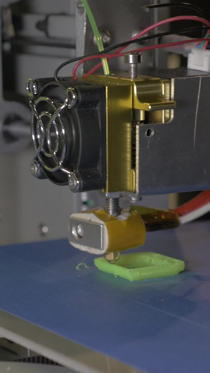 Modern 3D Printer Extruding Green Filament on Print Bed