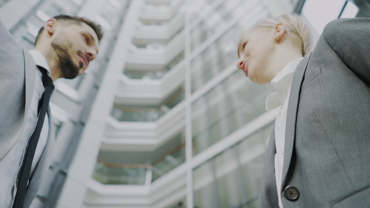 Businesspeople shaking hands in front of modern building