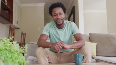 happy biracial man sitting on sofa and having video call