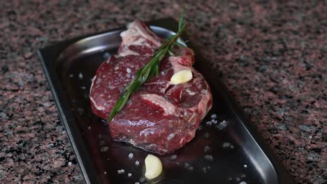 raw rib eye steak with rosemary and garlic