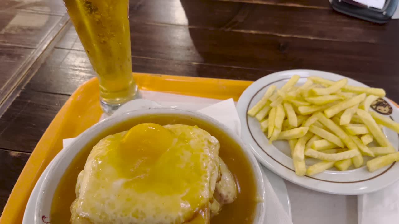 vista de cerca de un sándwich francesinha con una cerveza fría y papas fritas