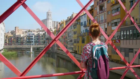 woman looking at onyar river on the middle of eiffel bridge in girona, spain