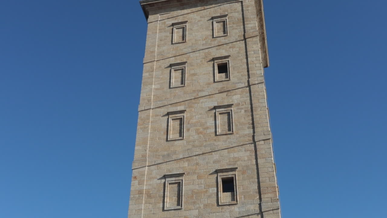 People sitting near the ancient Tower of Hercules on a sunny day in A Coruña Spain