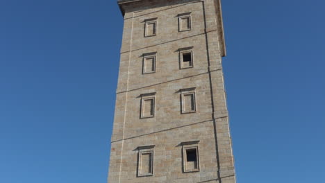 people sitting near the ancient tower of hercules on a sunny day in a coruña spain
