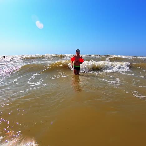 boy playing in the sea. bright summer day and small child having fun with foamy waves in the sea water. slow motion.