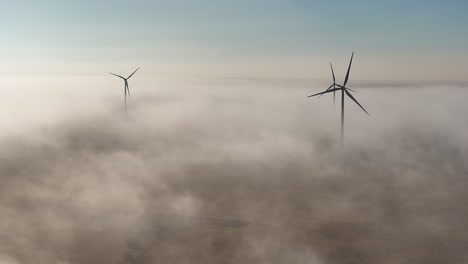 aerial view of a wind farm surrounded by fog at first light