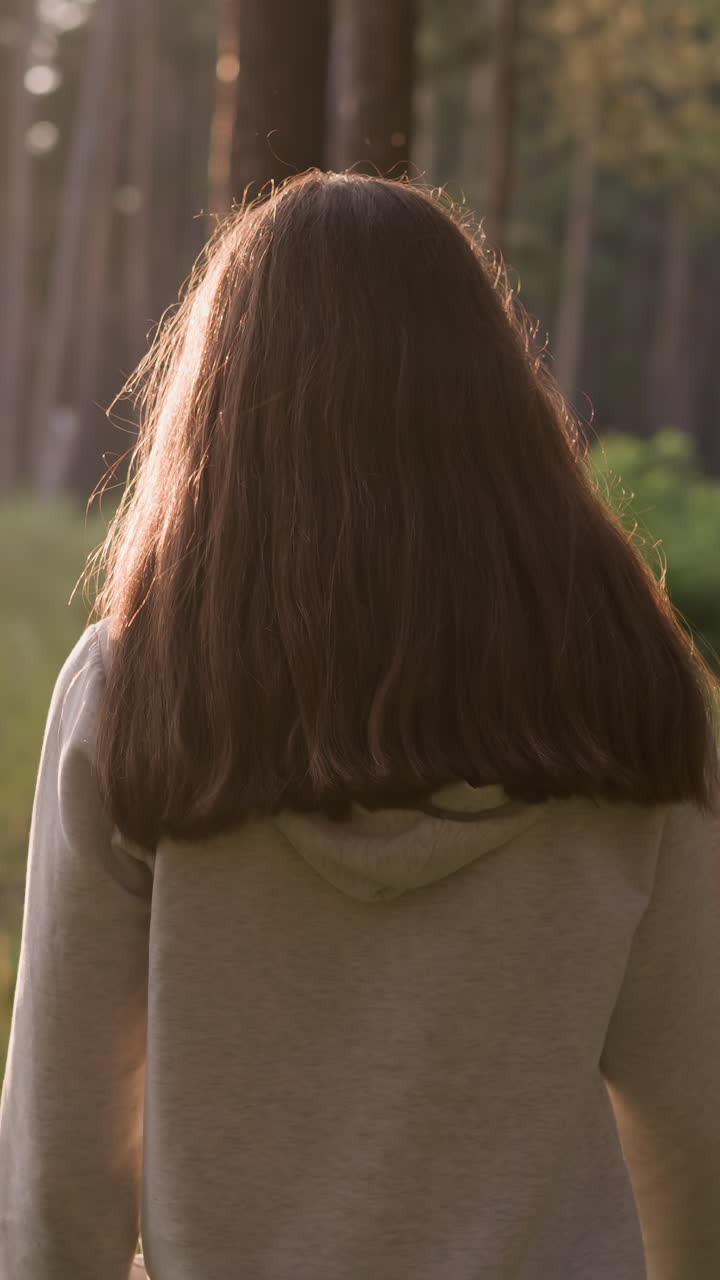 빛이 찬 숲을 고 있는 외로운 여인, 해가 지는 동안 나무와 야생 환경에 둘러싸인 혼자 산책하는 여인, 여자가  비어 있고 쓸모없다고 느다.