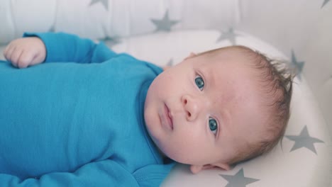 newborn baby with beautiful blue eyes lies on cocoon