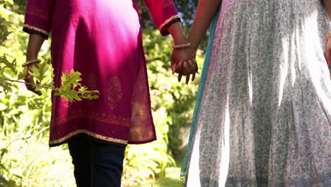 holding hands, two people walking together in traditional indian sari outdoors