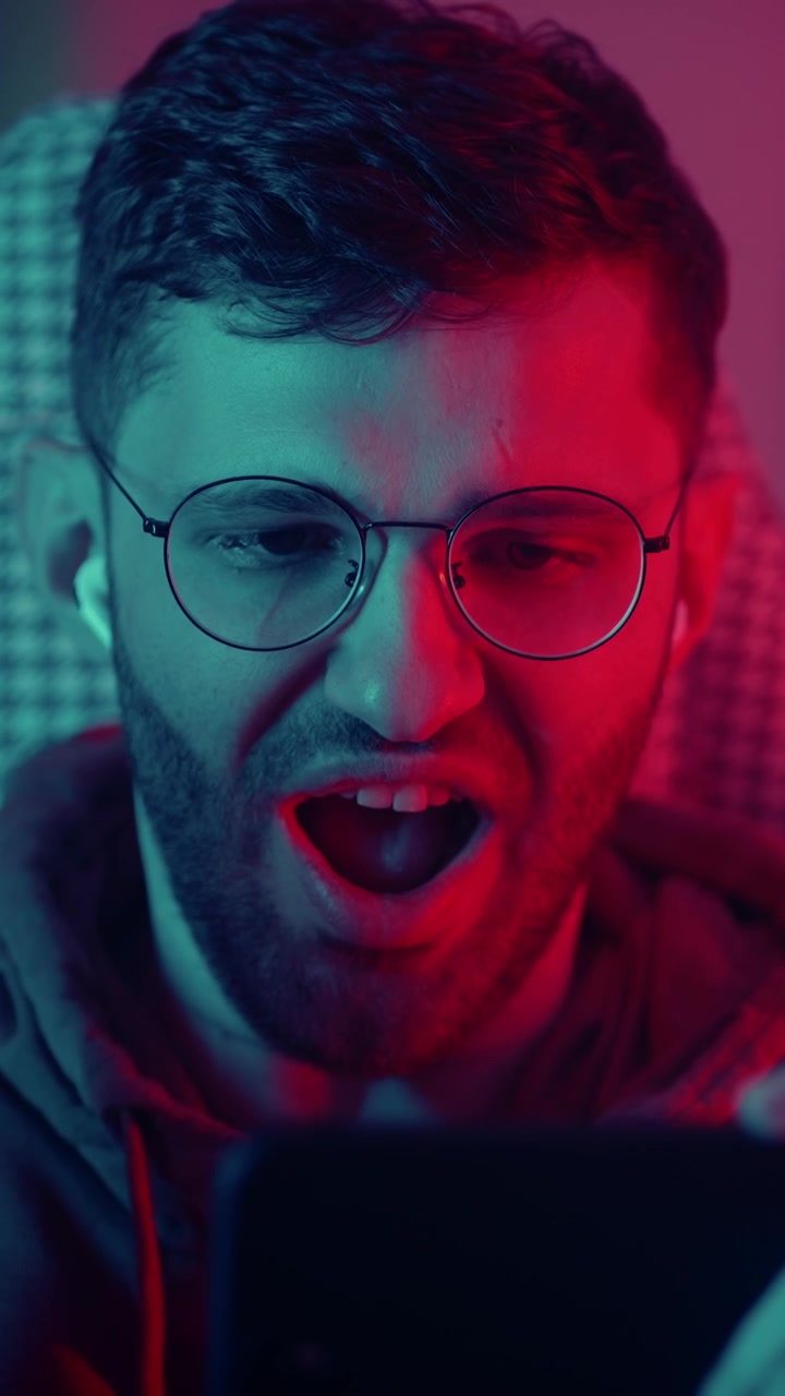 Ragazzo che gioca a un videogioco mobile con illuminazione al neon rossa e blu