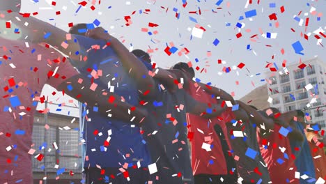 colorful confetti falling against team of standing together on grass field