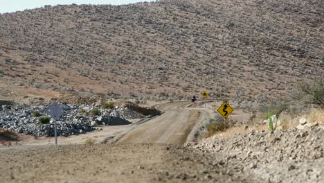 el motociclista se acerca a la cámara en una carretera de grava rústica en chile