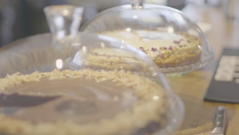 dolly shot of two cakes on a counter in a glass food stand at an modern small cafe