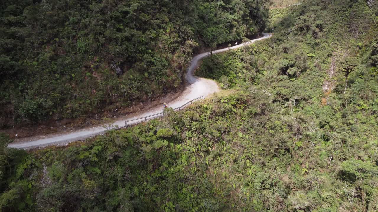 한 자전거 타는 사람 은 볼리비아 의 거친 지형 에서 휘어지는 산길 을 타고 내려간다