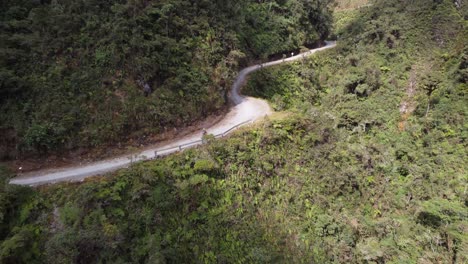 un ciclista baja por una sinuosa carretera de montaña en el accidentado terreno de bolivia.