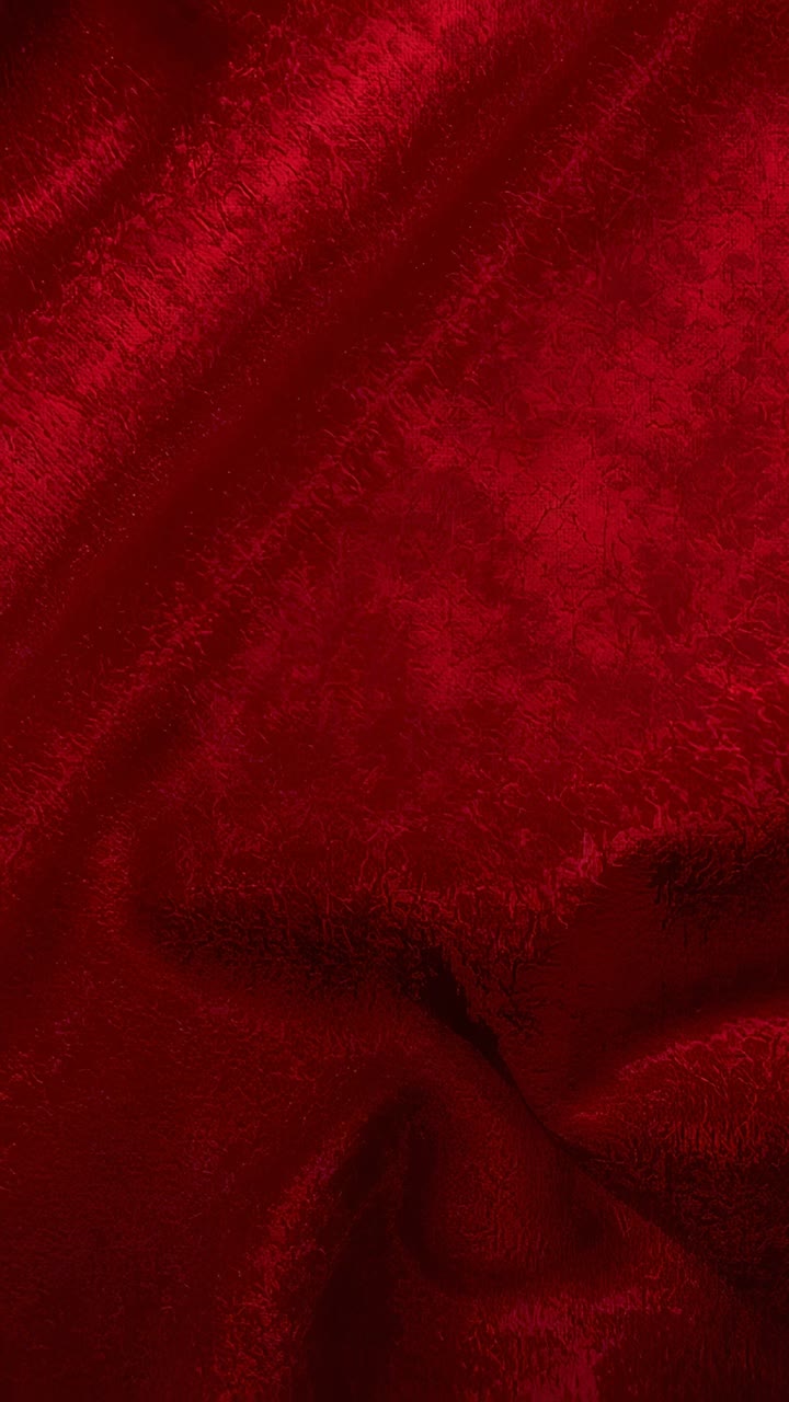 Video verticale: cinque fotogrammi che mostrano lo spostamento della superficie in velluto rosso e l'aumento della profondità delle pieghe a partire da un leggero spostamento