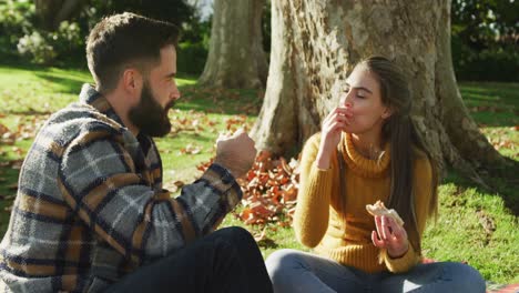 video of happy caucasian warmly dressed couple eating in the garden