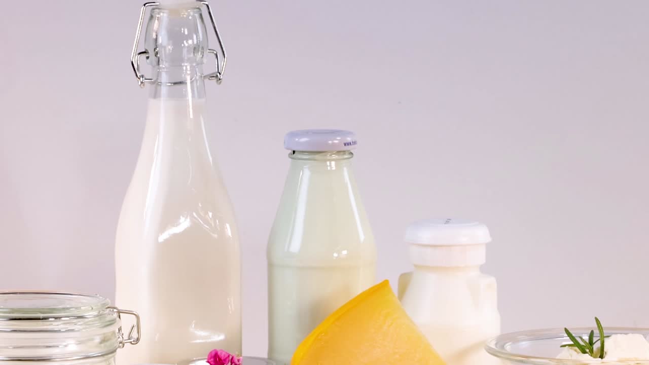 A variety of dairy items including milk bottles and cheese arranged on a wooden table.