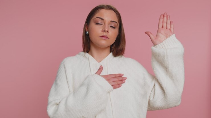 Sincere responsible young pretty woman raising hand to take oath, promising to be honest, tell truth