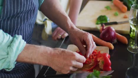 feliz pareja caucásica madura cocinando juntos y bebiendo vino en la cocina