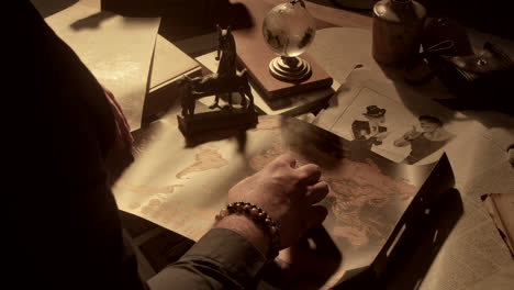 man studying vintage maps and documents at a desk