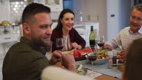 Happy-caucasian-father-smiling-to-camera-at-table-during-family-meal