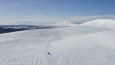 Vista-Aérea-De-Turistas-Montando-Motos-De-Nieve-A-Través-De-La-Nieve-En-El-Norte-De-Suecia-Durante-El-Invierno