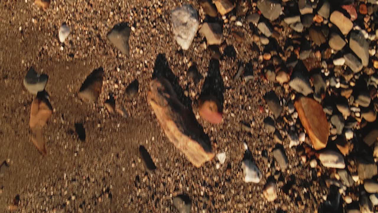 스페인 모래 해안 조약돌 해변 위의 낮은 각도 조감도는 작은 해안 마을 지평선까지 기울어져 있습니다.