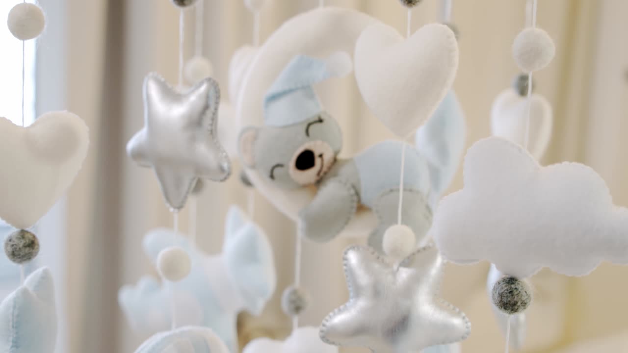 어린이의 부드러운 장난감은 요람 침대 위에서 원으로 회전합니다. 가까이 가십시오. 카메라를 움직이십시오.