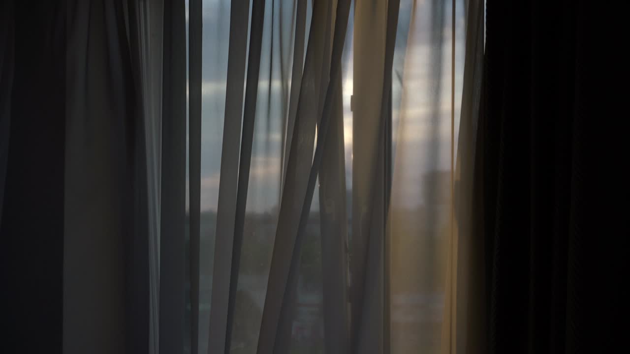 해가 지면 열린 창문 프레임을 통해 가운 바람이 불고 있습니다.