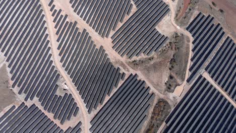 Drohne-Von-Oben-Nach-Unten-über-Reihenpaneele-Des-Photovoltaik-Solarparks,-Hügel,-Sonniger-Tag