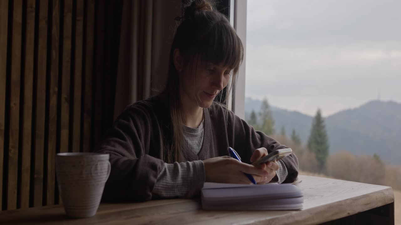 Donna che scrive sul diario con vista sulle montagne