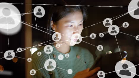 Animation-of-network-of-connections-with-icons-over-asian-casual-businesswoman-using-tablet