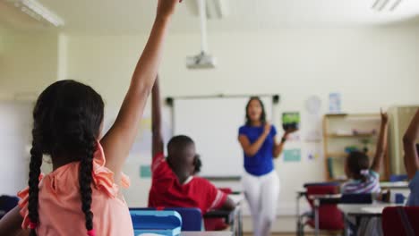mixed race female teacher standing in classroom asking questions abount plant during biology lesson