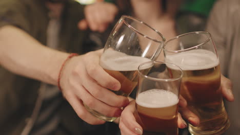Friends Toasting Beer Mugs At Bar