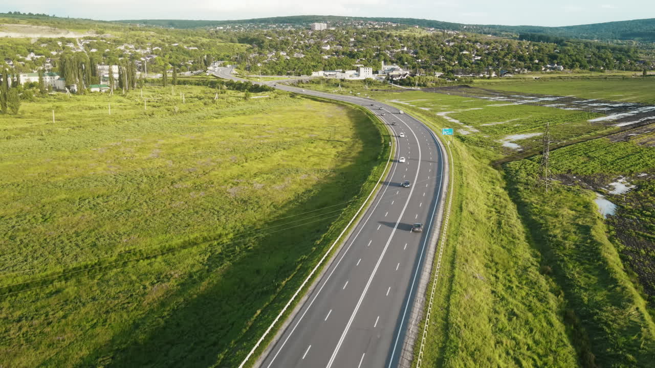 Aerial drone view of a highway with cars, village, a lot of greenery, fields in Moldova
