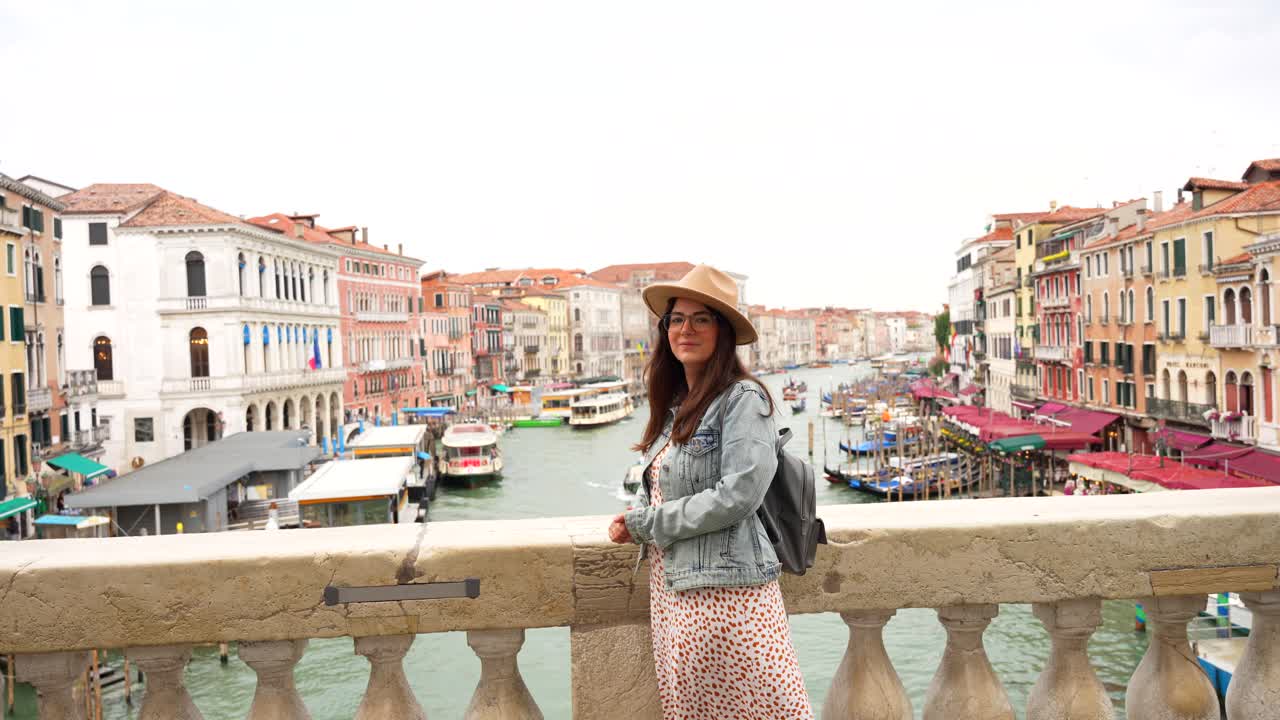 Female tourist enjoys sightseeing on Ponte Rialto over Grand Canal in Venice