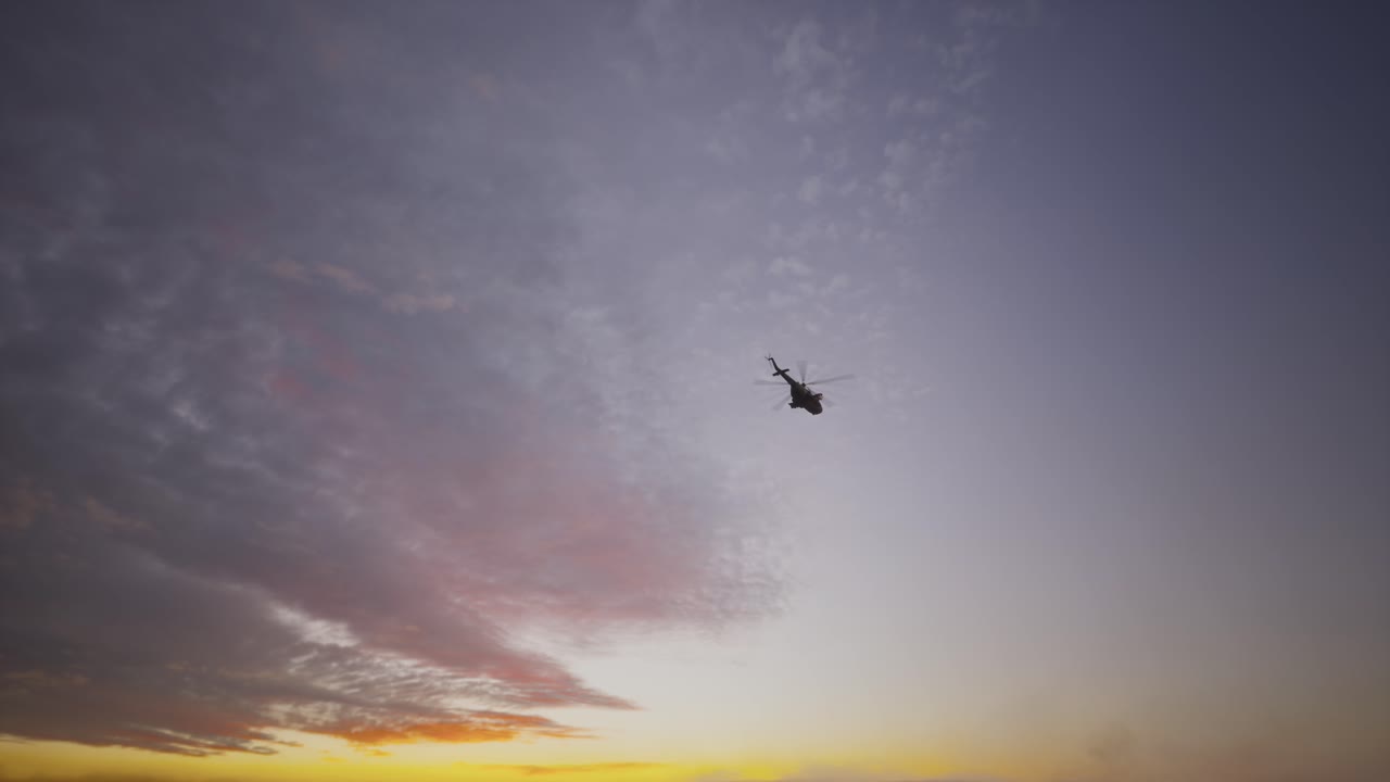 Militær transporthelikopter flyvende ved solnedgang eller solopgang