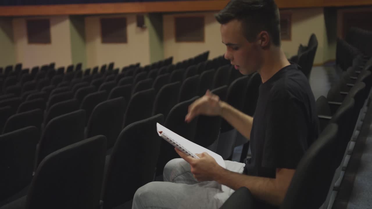 un adolescente caucásico de secundaria en el auditorio preparándose para una actuación