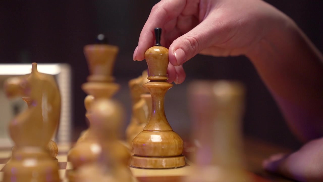 A Hand Moves a Wooden King Chess Piece on the Board